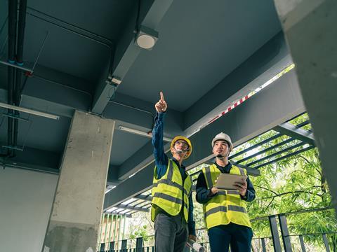 Men on a construction site consulting plans on a tablet