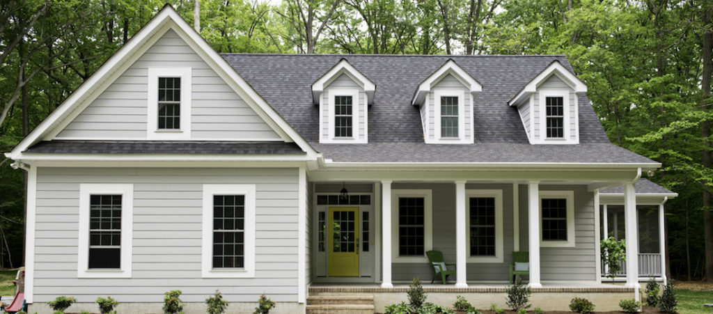 Exterior of a new Cape Cod styled suburban house with recently planted shrubs and grass